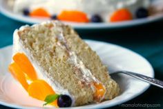 a slice of cake on a white plate with blueberries and oranges around it