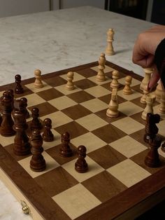 a person is playing chess on a wooden board