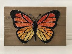 an orange and black butterfly painted on wood