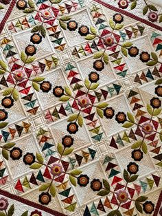 a quilted table topper with flowers and leaves on the edges, in various colors