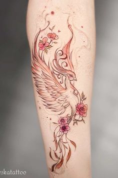 a woman's leg with tattoos on it and flowers in the shape of an eagle