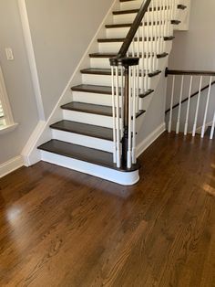 a white staircase with black railing and wood flooring