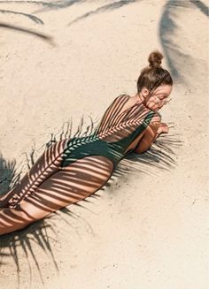 a woman laying on top of a sandy beach next to a palm frisbee