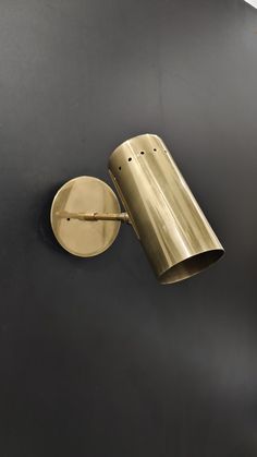 a wall light that is on the side of a black wall next to a clock