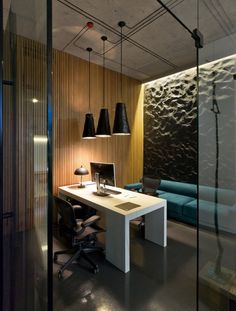 an office with glass walls and wood paneling on the wall, along with a white desk