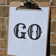 a clipboard with the word god on it next to a brick wall and clock