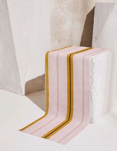 a pink and yellow striped rug sitting on top of a white floor next to a wall