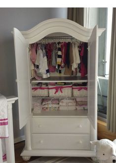 a baby's closet with white furniture and pink accessories on the floor next to a teddy bear