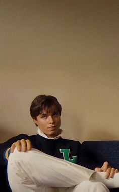 a young man sitting on top of a couch holding onto a piece of white paper