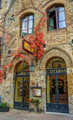 an old brick building with many windows and signs on the front, along with autumn foliage