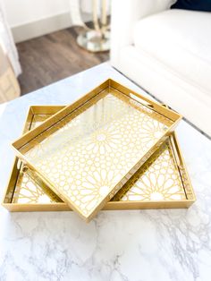 two golden trays sitting on top of a marble table