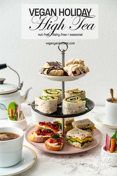 a plate with sandwiches and cup of tea on it next to a sign that says vegan holiday high tea