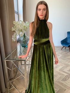 a woman in a green dress standing next to a table