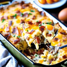 a casserole dish with eggs and bacon being lifted from the casserole