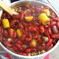 crawfish and corn on the cob are being cooked in a large pot