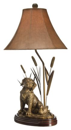 a lamp with a dog and reeds on the base is lit by a brown shade