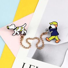 a pair of cartoon dog brooches sitting on top of a magazine next to a chain