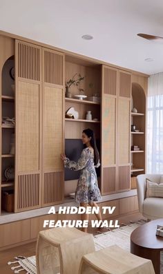 a woman standing in front of a wooden cabinet with the words hidden tv feature wall