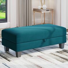 a blue footstool sitting on top of a rug in front of a window