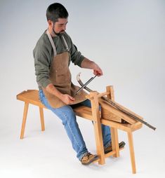 a man is sitting on a bench working with woodworking tools in front of him