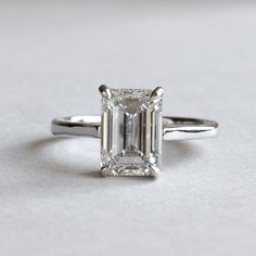 an emerald cut diamond ring on a white surface