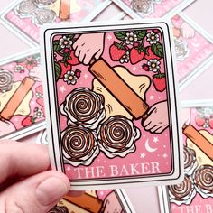 a hand holding up a sticker with the words the baker on it, surrounded by other stickers