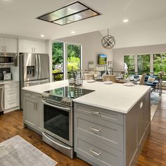 a large kitchen with stainless steel appliances and white counter tops, hardwood flooring in the middle