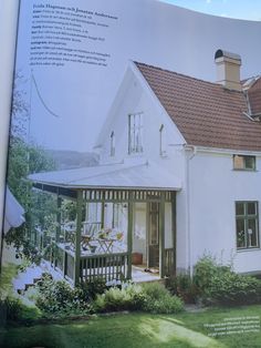 an open book showing a white house with a red roof and brown shingles on it