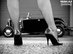 black and white photograph of woman's legs in fishnet tights with an old car