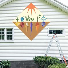 a house with a painting on the side of it and a ladder in front of it