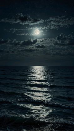 the moon is shining over the ocean at night with clouds in the sky and water