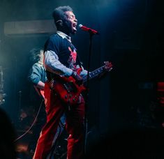 a man standing on top of a stage holding a guitar