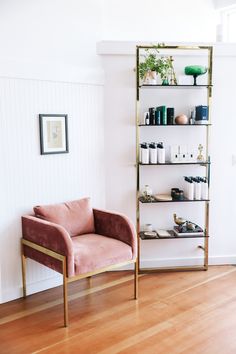 a pink chair sitting next to a shelf filled with bottles