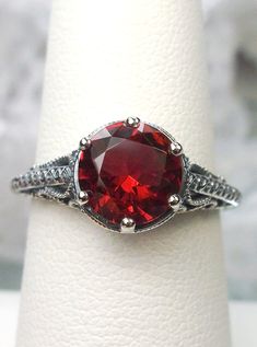 Simulated Ruby Ring Description  Spade Design#167 MADE TO ORDER Here we have an Art Deco/Edwardian inspired ring in sterling silver filigree with a perfect Simulated Red Ruby gemstone solitaire. This full cut round cut red ruby is 8mm in diameter. The setting is 9mm NS on the finger. The inside of the band is marked 925 for sterling. Notice the beautiful etched royal design of the silver filigree setting. A gift ring box is included and all rings are shipped in the white box for safekeeping. Fee Garnet Wedding, Red Coral Earrings, Red Opal, Silver Gold Jewelry, Filigree Pendant, Opal Earrings Stud, Opal Studs, Sterling Silver Filigree, Filigree Ring