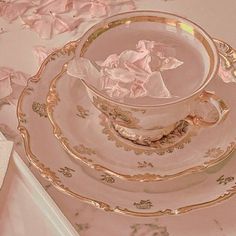 a pink and gold china tea set on a table