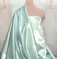 a mannequin wearing a green satin dress