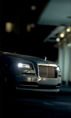 a black rolls royce parked in a parking lot at night