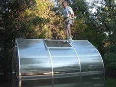 a man standing on top of a metal structure in the middle of some trees and bushes