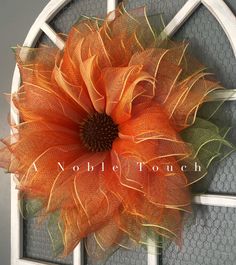 an orange flower on the front door of a house that is decorated with mesh netting