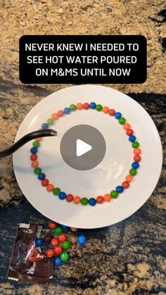 a white plate topped with lots of candy on top of a counter next to a chocolate bar