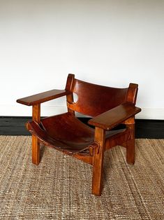 a wooden chair sitting on top of a carpeted floor next to a white wall