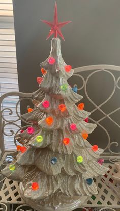 a white ceramic christmas tree with colorful lights on it's base and a star hanging from the top