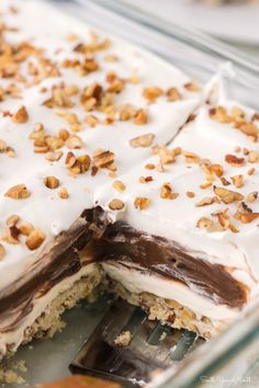 a cake with white frosting and nuts on top is being cut by a fork