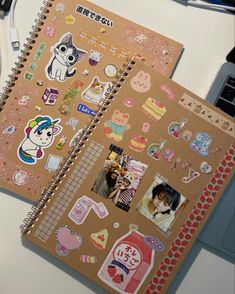 two notebooks covered in stickers sit on a desk