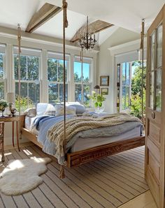 a bedroom with a canopy bed and lots of pillows on the floor, windows to the outside