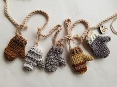 five knitted mittens hanging from twine on white surface with string attached to them