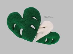 two green and white knitted mittens sitting next to each other on a gray background