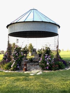 an outdoor gazebo with flowers growing around it