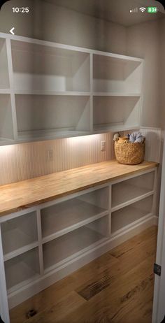 an empty room with white shelves and wood flooring