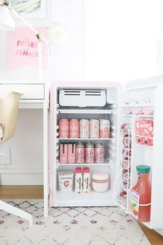 an open refrigerator sitting on top of a rug next to a white desk and chair